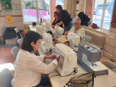 Un grup de voluntàries participen al taller, fent servir les màquines de cosir.